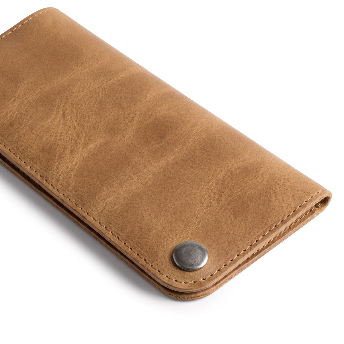 Side view of the Red Double Snap Folio Wallet by Hide & Drink, exhibiting its supple full grain leather. This artisan-crafted wallet serves as a stylish rectangular flat bill holder with card slot, perfect for a night bag or travel accessory, made with care in La Antigua Guatemala & Oaxaca Mexico.