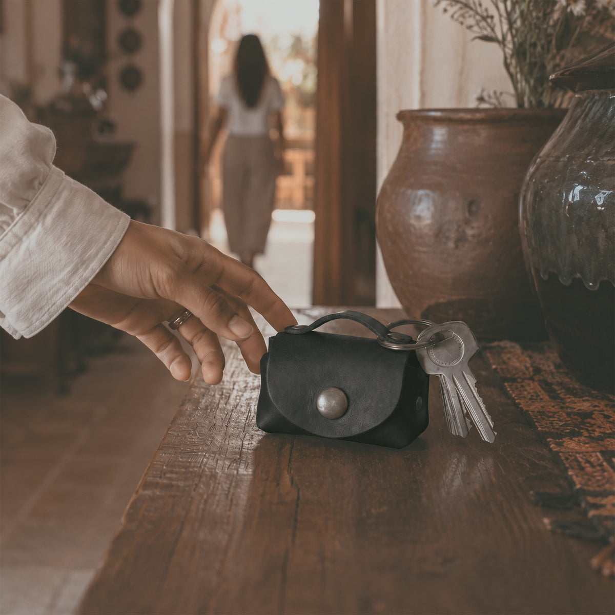 Interior view of the black Tiny Handbag Keychain by Hide & Drink, displaying keys and coins. Crafted from Full Grain Leather, this artisanal product represents small batch production and showcases excellent hand cut and hand sewn craftsmanship.