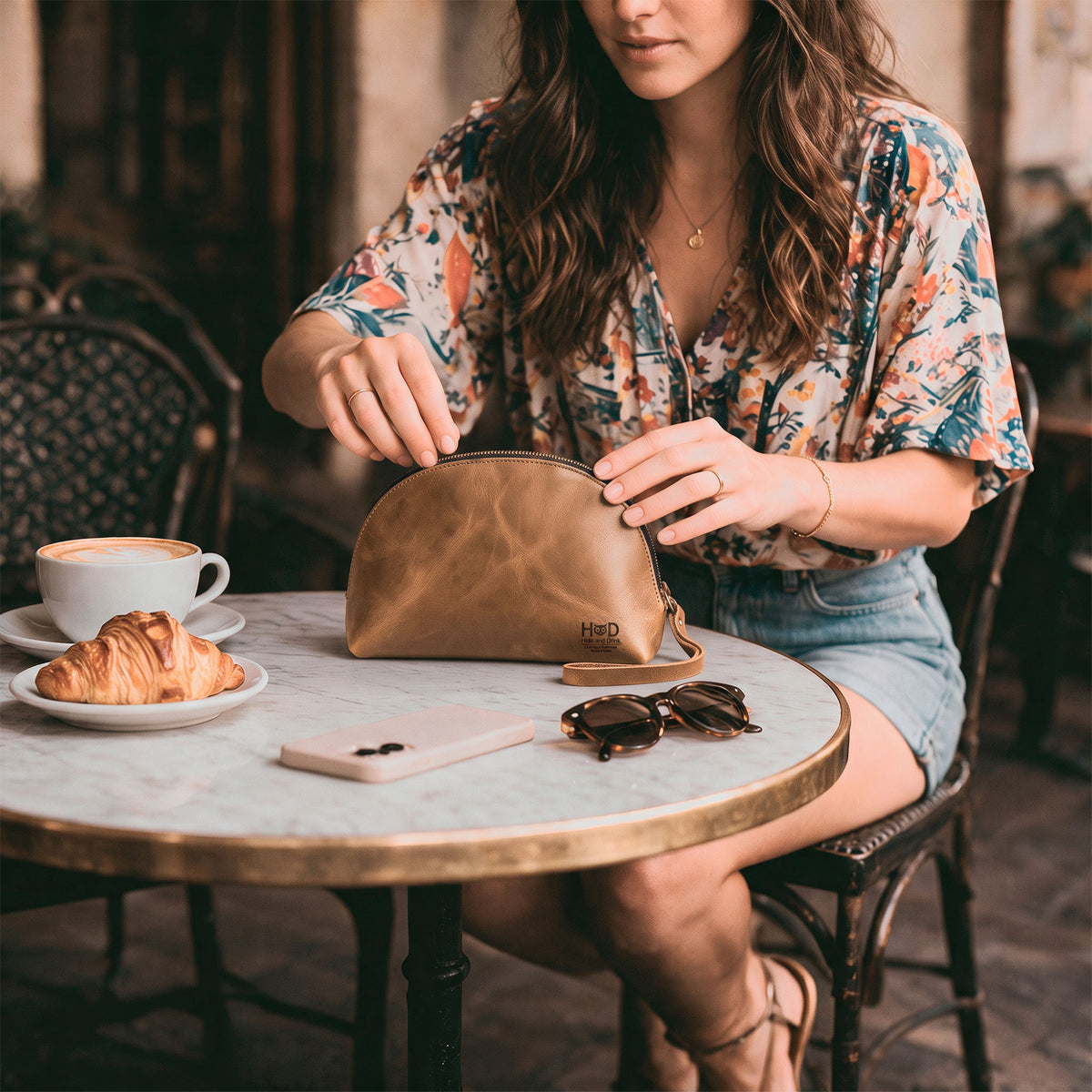 The Accessory Pouch Organizer Hand Bag by Hide & Drink alongside a business card, showcasing artisan craftsmanship in brown full grain leather. This Cosmetic Travel Organizer with Hand Strap for Women serves as an ideal Makeup Bag and Classic Handbag, handmade in La Antigua Guatemala & Oaxaca Mexico.