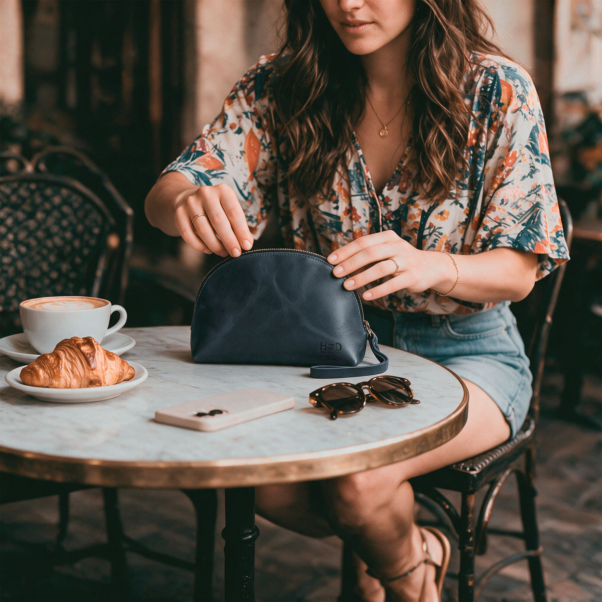 The Accessory Pouch Organizer Hand Bag in brown from Hide & Drink, displayed with a business card showcasing its artisan heritage. This fashionable Cosmetic Travel Organizer with Hand Strap for Women serves as a reliable Makeup Bag and Classic Handbag, handmade in La Antigua Guatemala & Oaxaca Mexico.