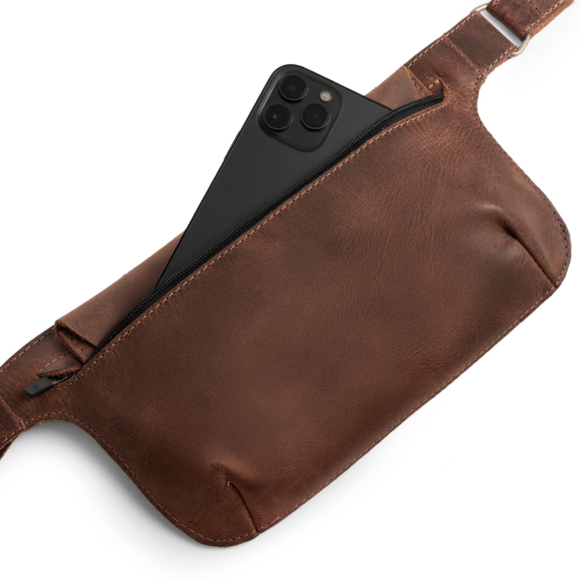 Slim Fanny Pack by Hide & Drink with an open pocket revealing keys and a smartphone, designed as a rectangular fanny pack with an adjustable strap. This artisan-crafted waist bag features durable full grain leather, handmade in La Antigua Guatemala.