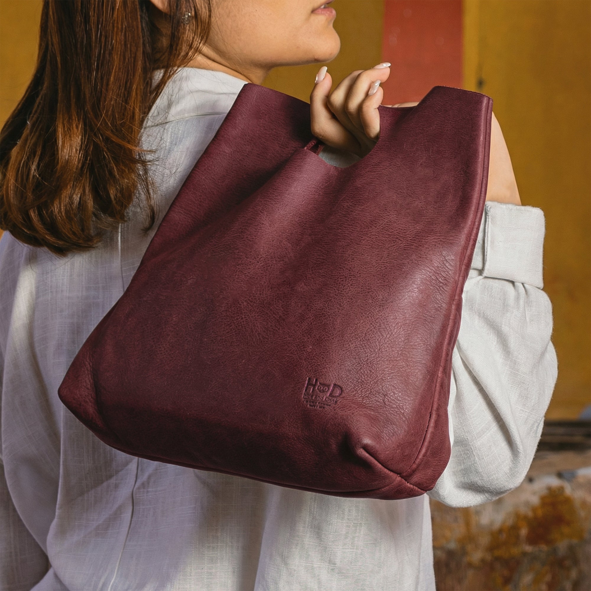 An overhead view of the red Minimalist Boho Handbag by Hide & Drink, filled with accessories like a phone and wallet. This Minimalist Handbag for Women doubles as a practical Tote Bag, crafted from elegant Full Grain Leather, promoting StockyardX's commitment to artisan craftsmanship through Hand Cut techniques made in La Antigua Guatemala & Oaxaca Mexico.