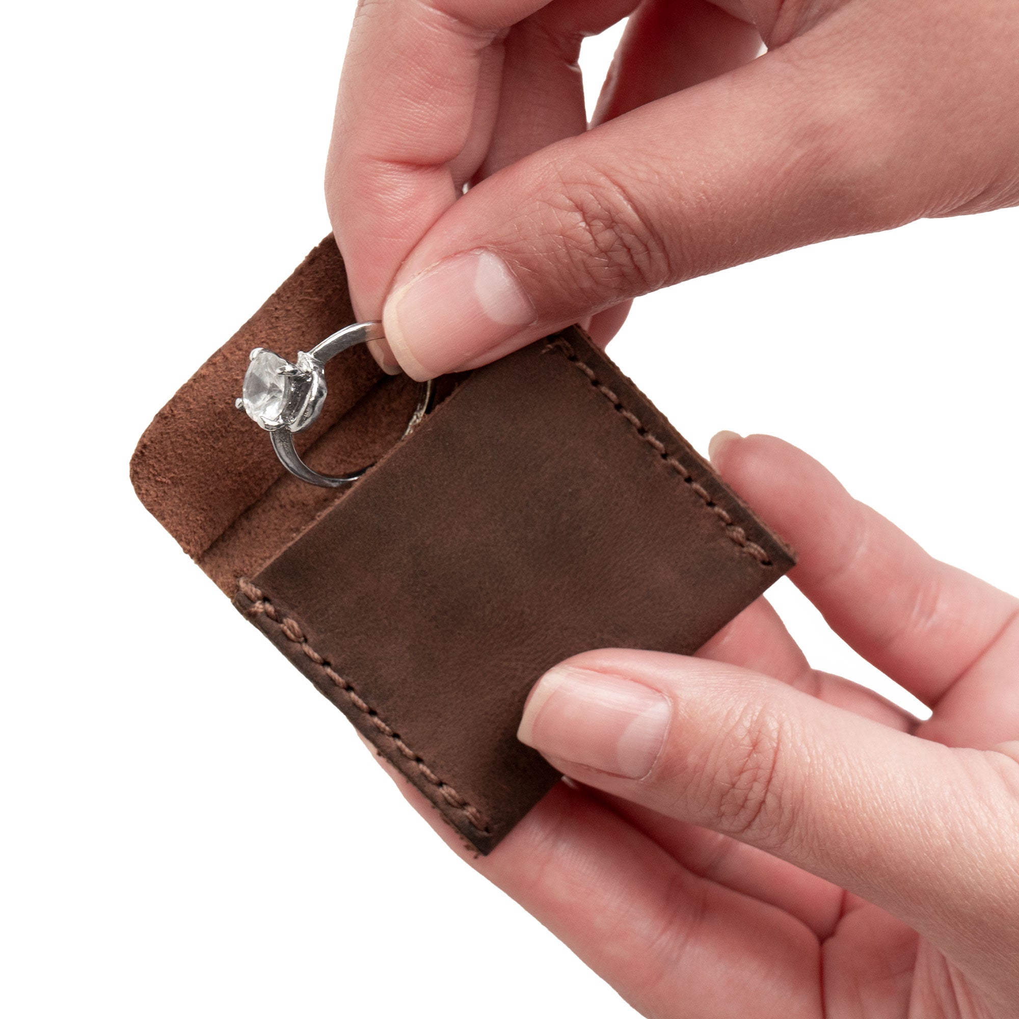 A hand holding Heather's Wedding Ring Case while demonstrating its practical use as an engagement pouch for bride and groom jewelry. Ideal for marriage travel or a ring bearer, this case is crafted from full grain leather, representing quality small batch production. Each item is handmade in La Antigua Guatemala & Oaxaca, ensuring unique details through hand cut and hand sewn craftsmanship with a signature fire branded logo.