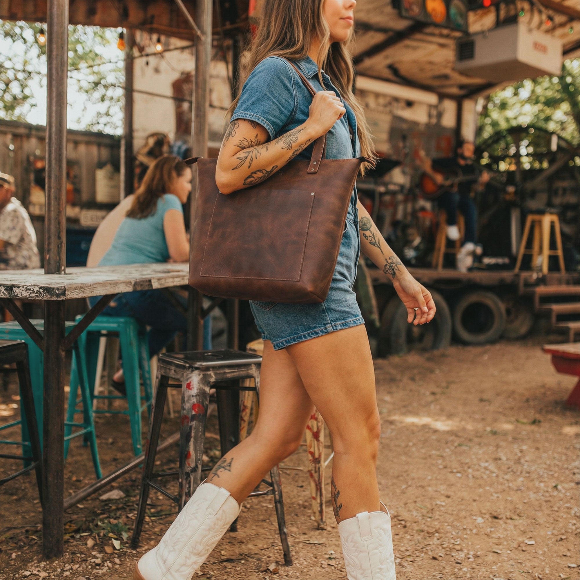 Lifestyle image of The Juniper Zippered Tote Bag being carried outdoors, capturing the spirit of Austin. This handmade bag combines artistry and practicality, made from full grain leather with inspiration drawn from the unmistakable Texas vibe. Crafted in La Antigua Guatemala and Oaxaca Mexico.