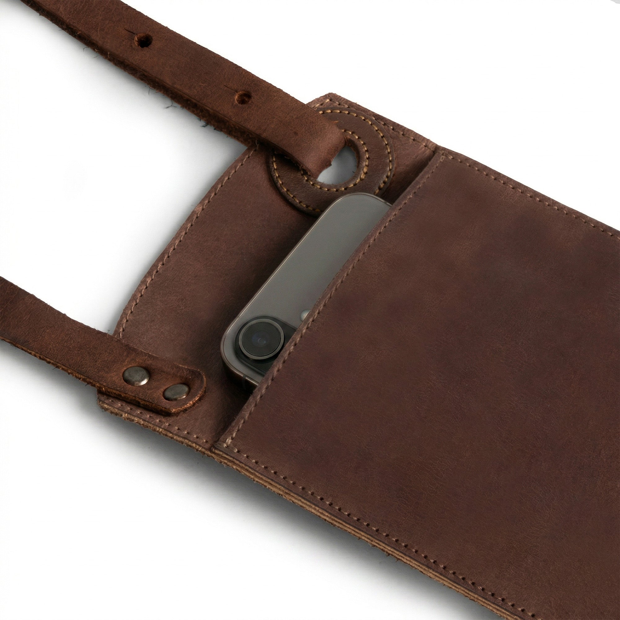 Close-up of the Phone Purse with Adjustable Strap by Heather's, highlighting the smooth full grain leather and its practical design with card slot. This horizontal cellphone bag features an adjustable strap making it versatile as a crossbody or mini messenger bag. Hand sewn and cut by artisans in La Antigua Guatemala, this bag exemplifies quality craftsmanship.