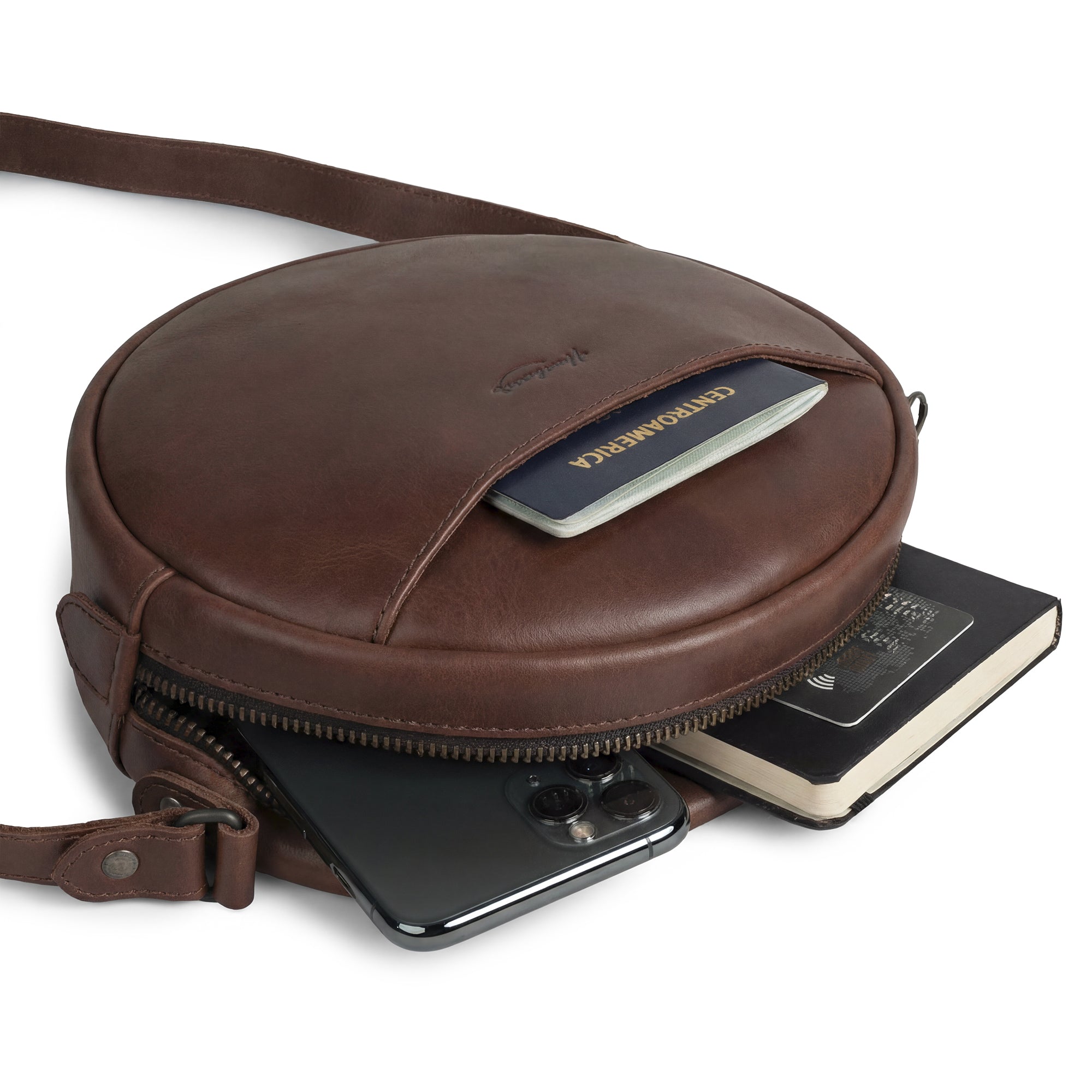 Heather's Female Rounded Crossbody Hand Bag open to show contents including essentials. Made with Full Grain Leather, this zippered handbag for women is versatile and chic. Perfect as a shoulder bag for girls, the bag features handmade qualities with meticulous attention to detail from artisan production in La Antigua Guatemala.