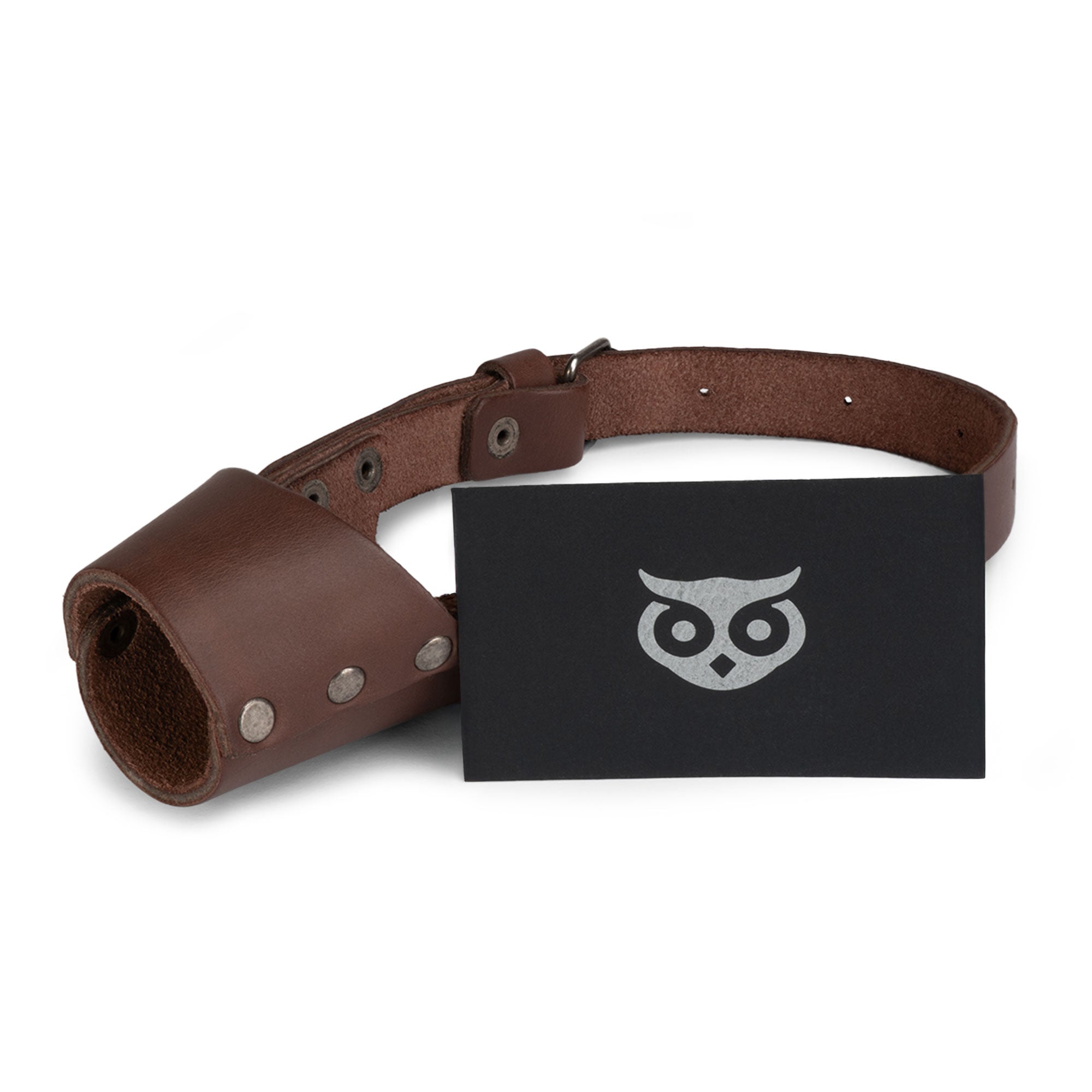 Riveted Dog Muzzle presented by Hide & Drink alongside branded merchandise, emphasizing its secure and effective design for dog protection. This full grain leather muzzle guard is crafted for preventing biting and chewing, fitting all breeds including Pitbulls and German Shepherds, and is handmade in La Antigua Guatemala & Oaxaca Mexico.