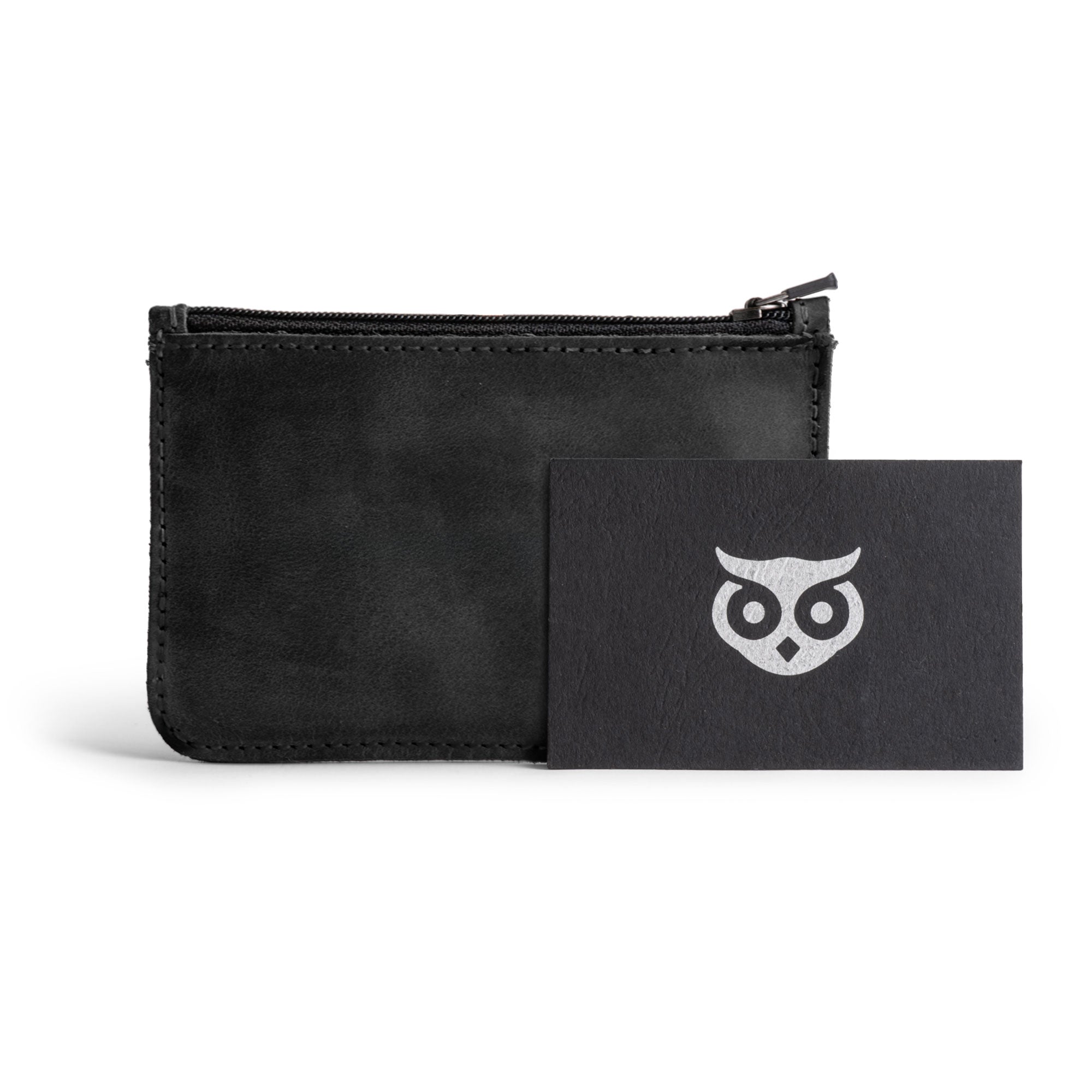 Hide & Drink zippered wallet alongside a crafted card, showcasing the brand's commitment to artisan quality and handmade production. Perfect for organizing your cash, cards, and coins, this full grain leather wallet is a stylish addition to your accessory collection.