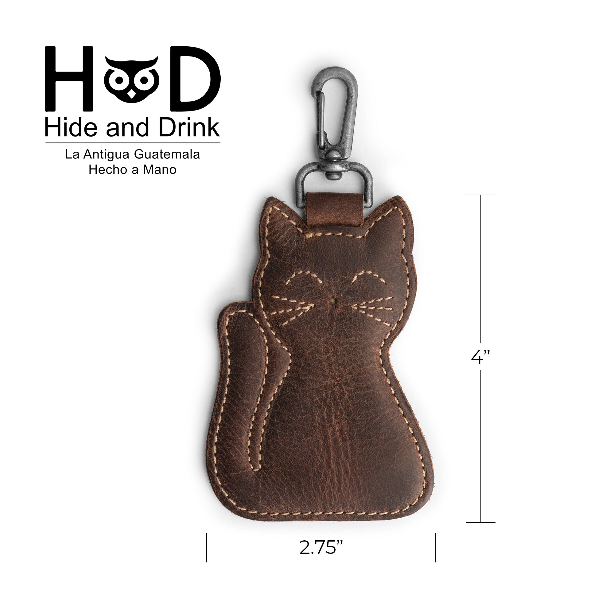 Dimensions of the Cat Keychain by Hide & Drink displayed with measurements. This Cat-Shaped Keychain is both a functional key organizer and a delightful stuffed animal-shaped ornament made from Full Grain Leather. Each handmade piece reflects artisan skills from La Antigua Guatemala and Oaxaca, Mexico, with features like hand cut and hand sewn details and a unique fire-branded logo.
