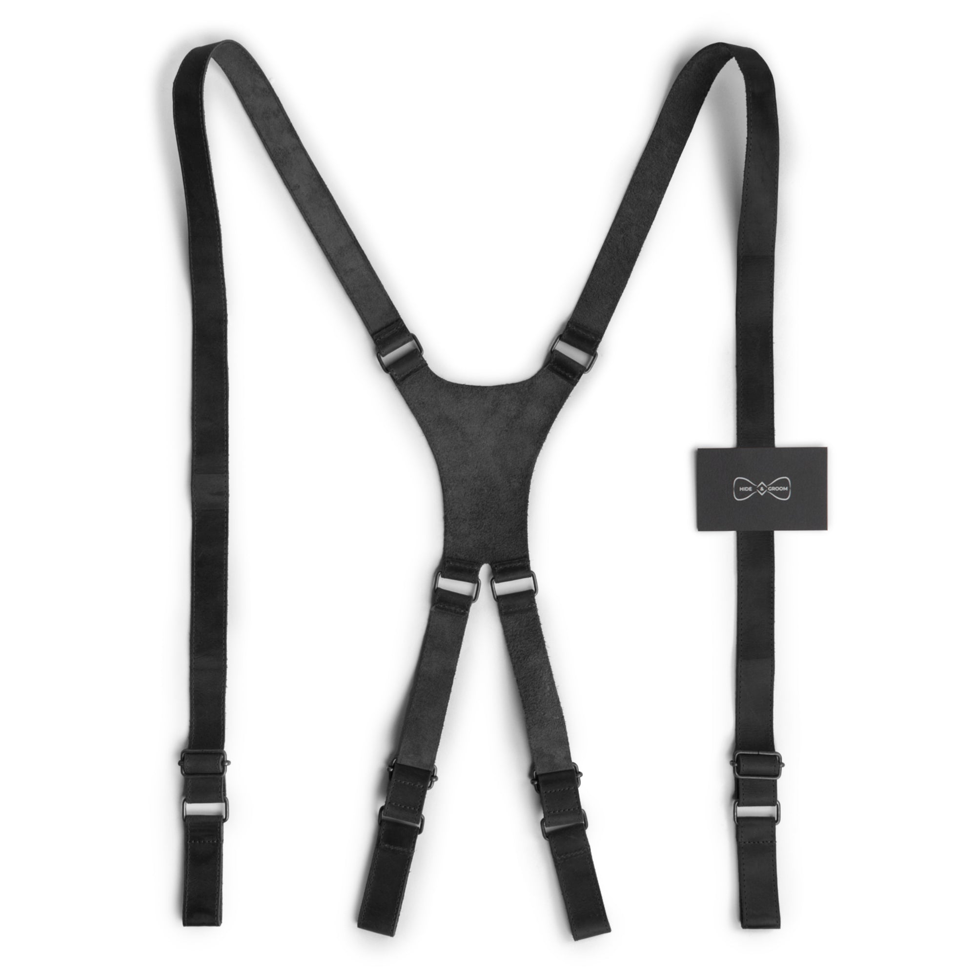 X Back Formal Suspenders in sleek black with product tags by Hide & Groom, showcasing artisan craftsmanship with full grain leather. Essential for weddings, these suspenders provide shoulder support and a stylish look. Handmade and fire branded, each piece reflects the quality of small batch production in La Antigua Guatemala.