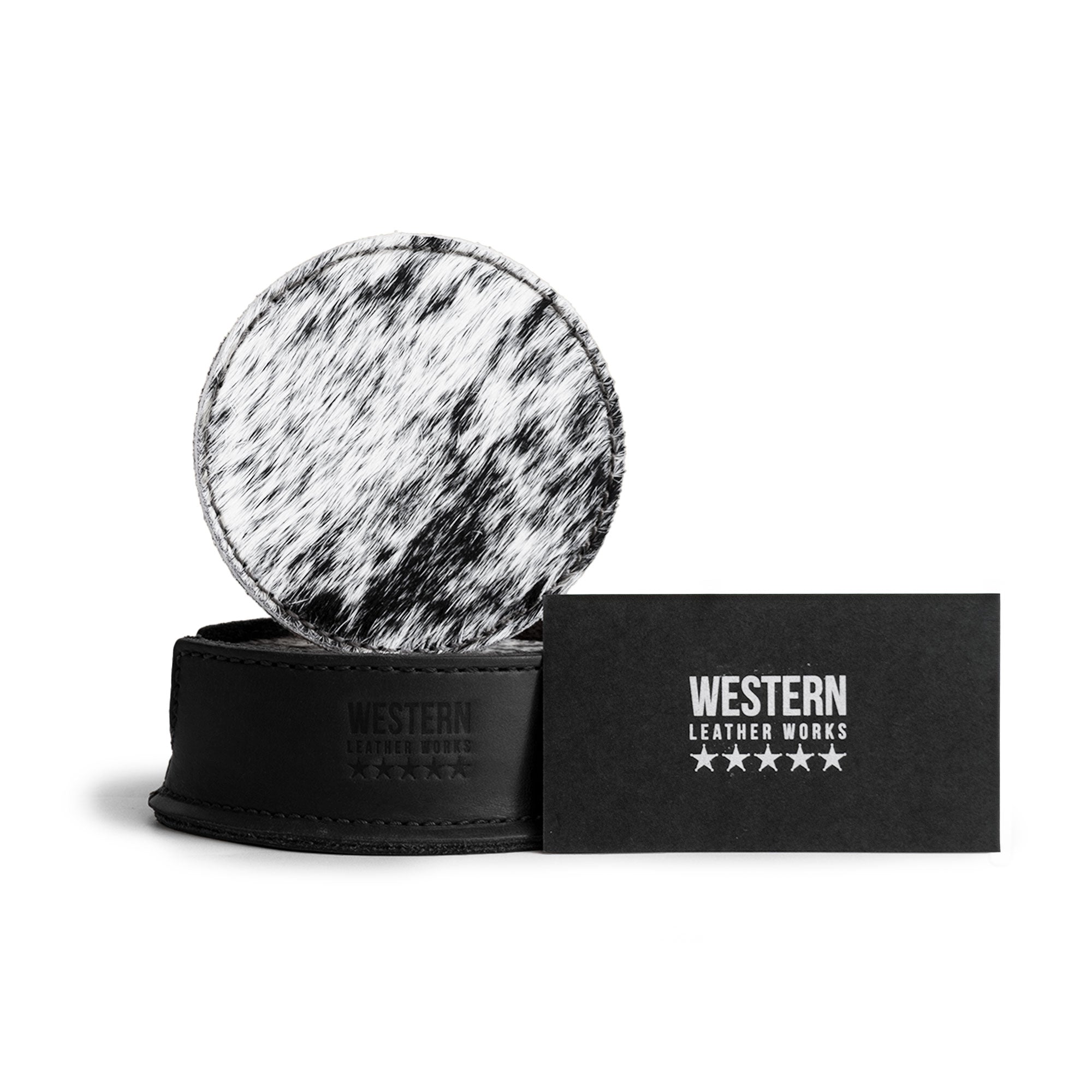 The Western Leather Works logo and a hair-on-hide coaster are captured next to a card, part of the Set of 6 Circular Coasters for Drinks, designed for optimal Glass & Cups Stain Protection. Crafted from Full Grain Leather through small batch production, this artisan item features hand cut, hand sewn details, and fire branding, reflecting the quality and heritage of handmade goods from La Antigua Guatemala & Oaxaca Mexico.