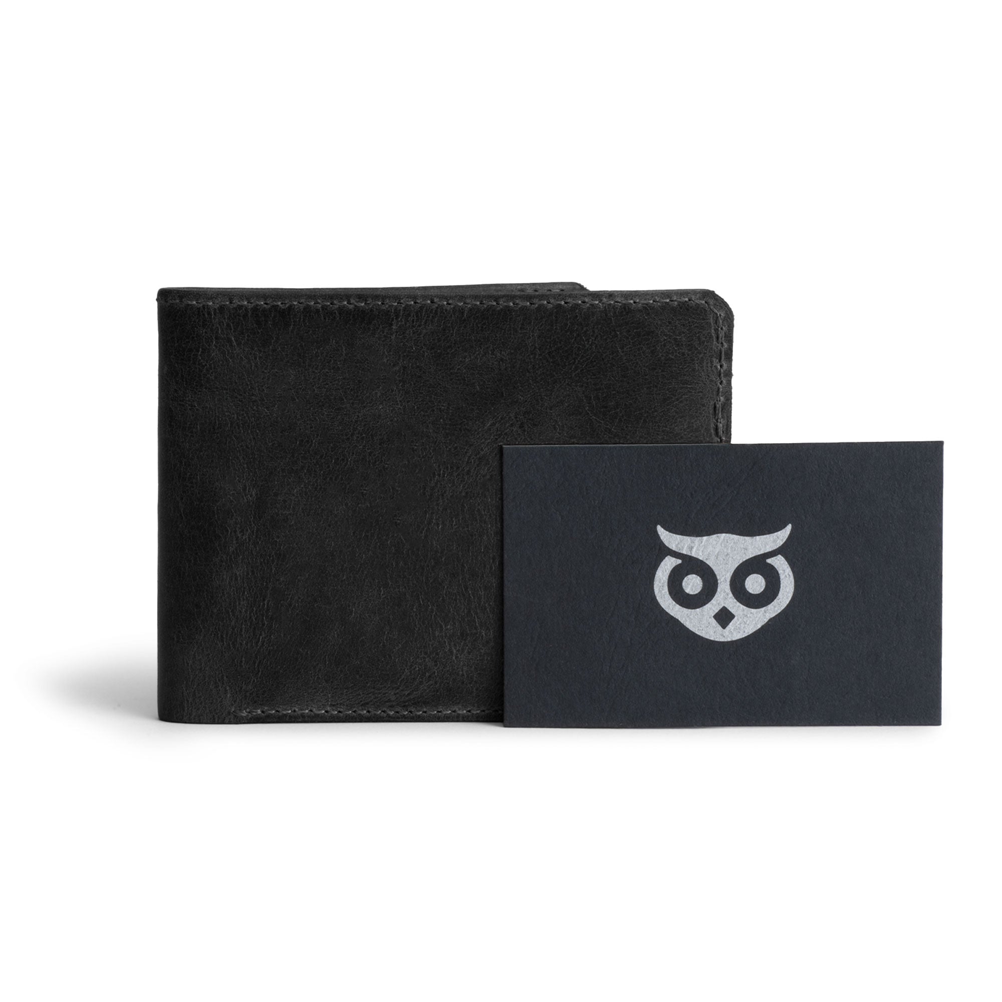 Hide & Drink's black Bifold Wallet next to a Stockyard Exchange card, emphasizing artisan craftsmanship. This Slim Bifold Wallet acts as a classic billfold perfect for organization of money and cards, serving as an essential travel accessory handcrafted from full grain leather in La Antigua Guatemala & Oaxaca Mexico.