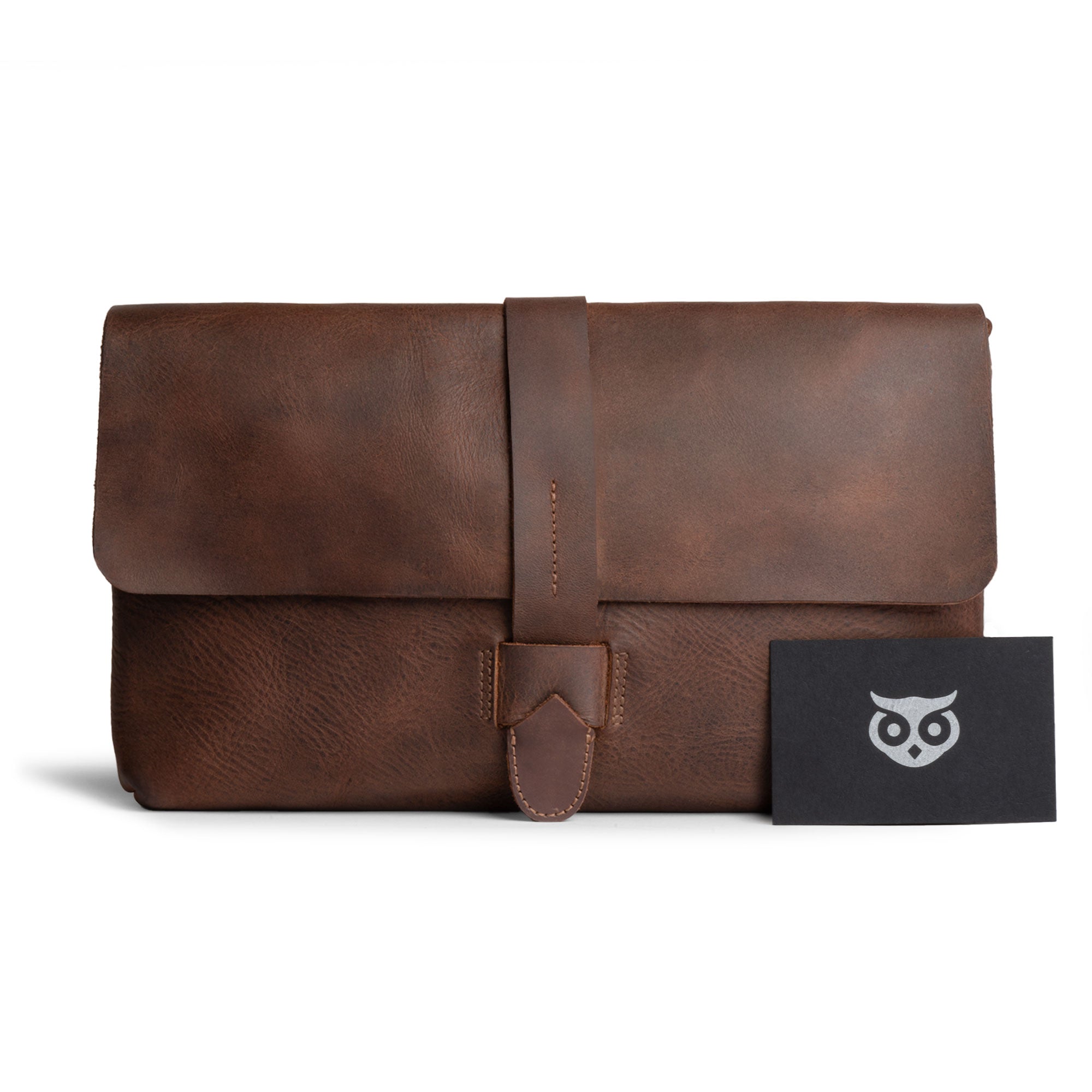 Hide & Drink Snapless Clutch Bag presented with a card, highlighting its artisan craftsmanship and full grain leather material. This handmade handbag serves as a versatile case for your phone and accessories, proudly made in La Antigua Guatemala to meet high-quality standards.