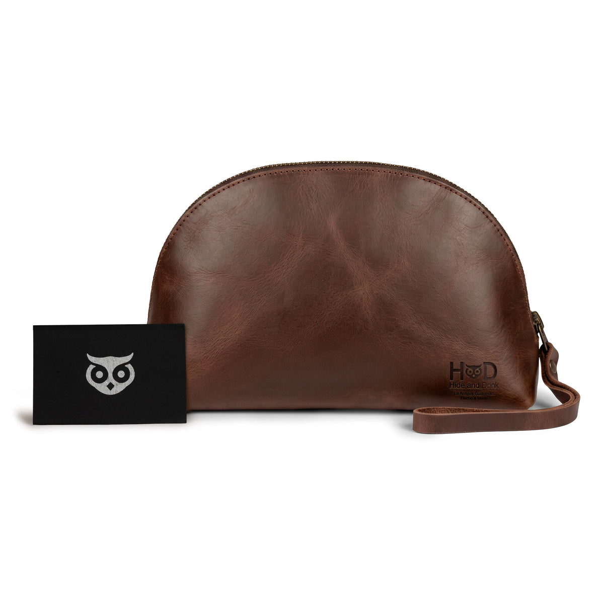 The Accessory Pouch Organizer Hand Bag by Hide & Drink, alongside a business card, highlighting its full grain leather craftsmanship. Ideal as a Cosmetic Travel Organizer with Hand Strap for Women or as a Makeup Bag and Classic Handbag, handcrafted in La Antigua Guatemala & Oaxaca Mexico.