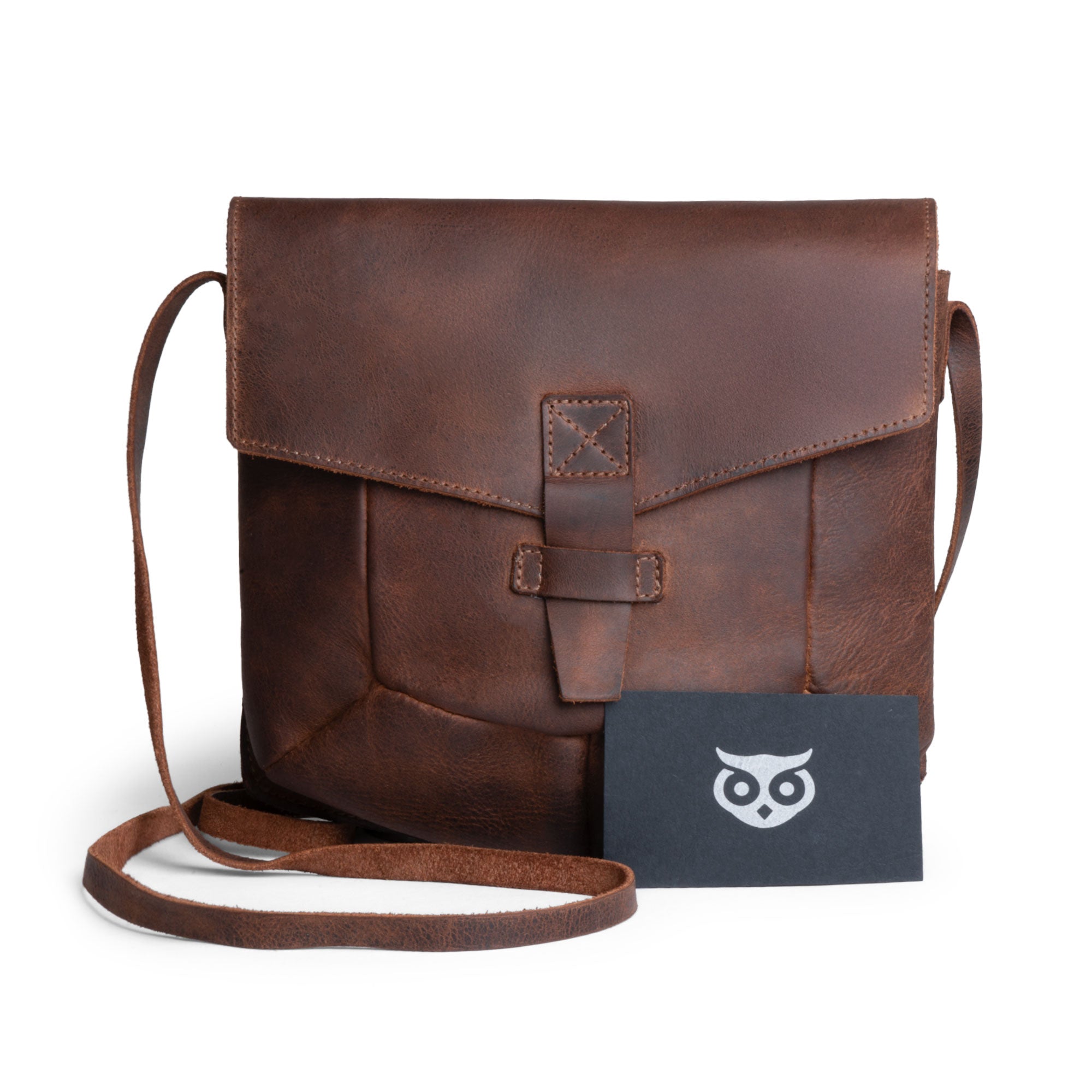 The Prisma Shoulder Bag from Hide & Drink with a business card alongside it, demonstrating its practicality and style. This vintage purse serves as a beautiful messenger and crossbody bag made from full grain leather, reflecting the small batch artisan production from La Antigua Guatemala & Oaxaca Mexico.