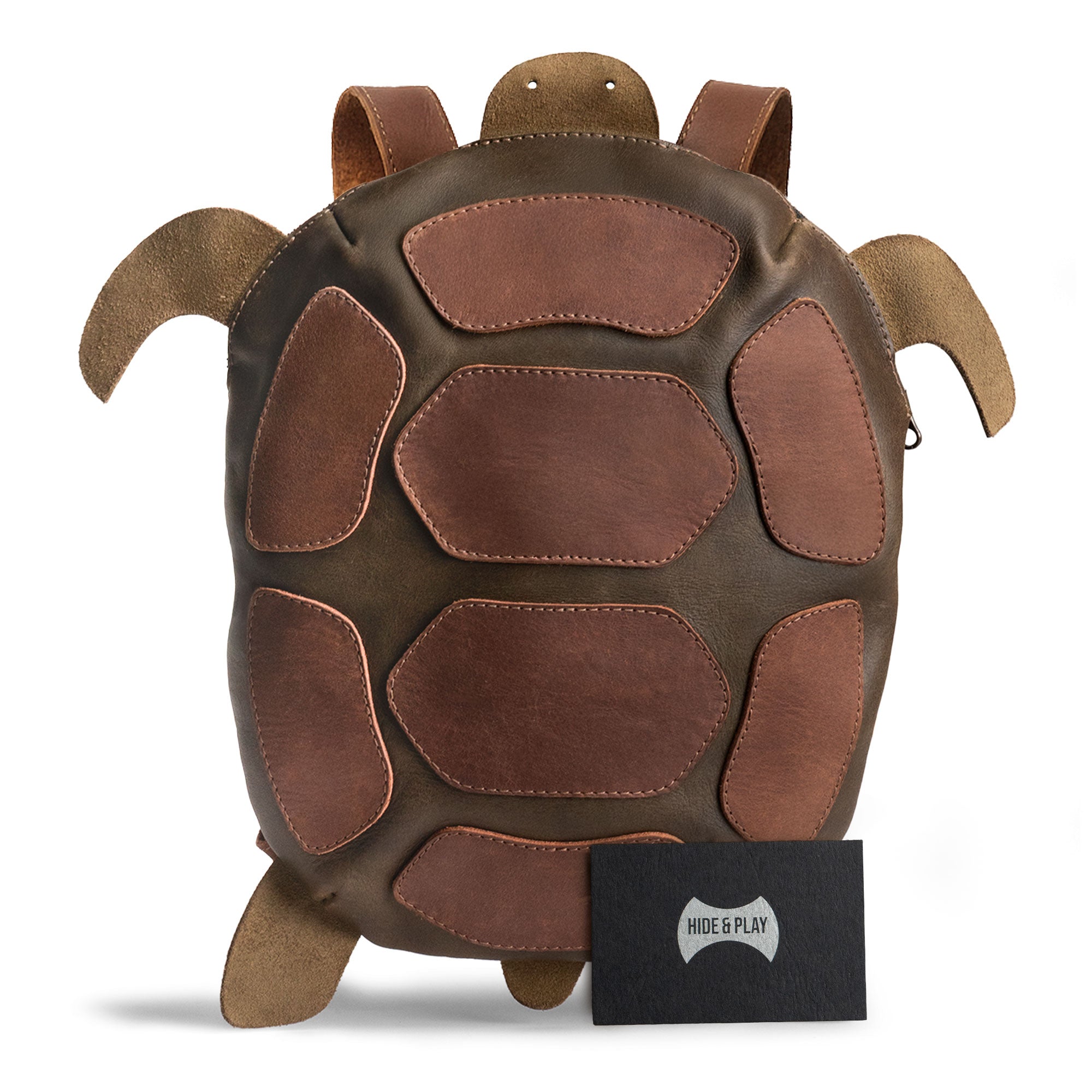 The Turtle-Shaped Backpack by Hide & Play displayed with tags and artisan cards, emphasizing its handmade quality. This bag serves as a stylish Casual Bag, Messenger Bag, or Travel Bag for Men and Women. Made of Full Grain Leather, it illustrates StockyardX's Small Batch Production style, with each piece being hand cut, hand sewn, and fire branded by artisans in La Antigua Guatemala.
