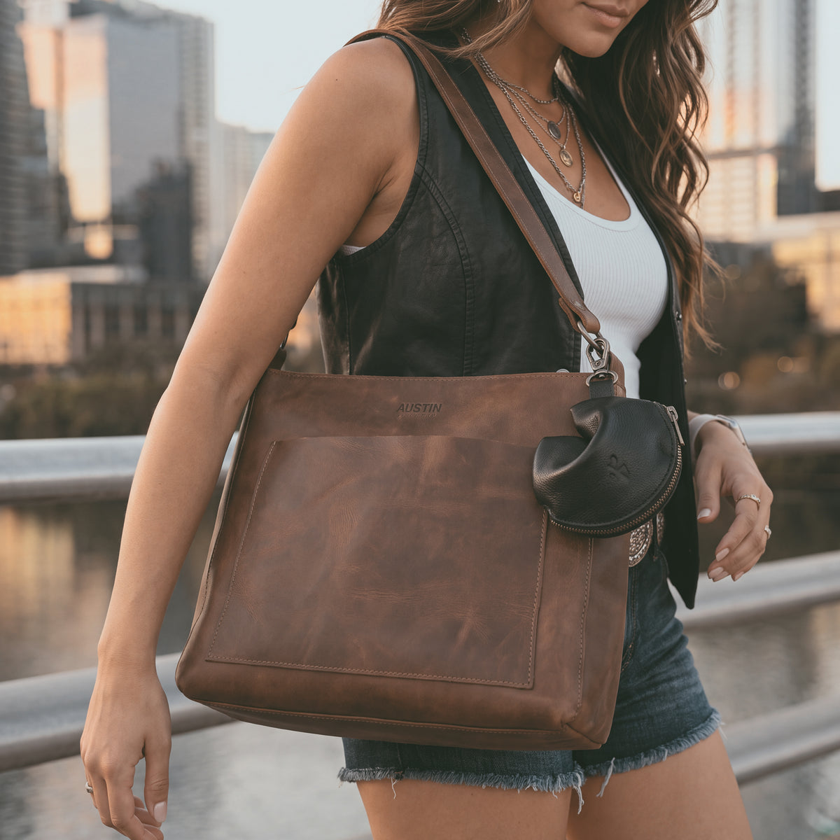Austin Genuine The Bouldin Fortune Cookie Pouch in black Full Grain Leather styled on a shoulder bag for everyday wear; StockyardX Small Batch Production, Hand Cut, Hand Sewn, Fire Branded, Artisan, Handmade in La Antigua Guatemala & Oaxaca Mexico.