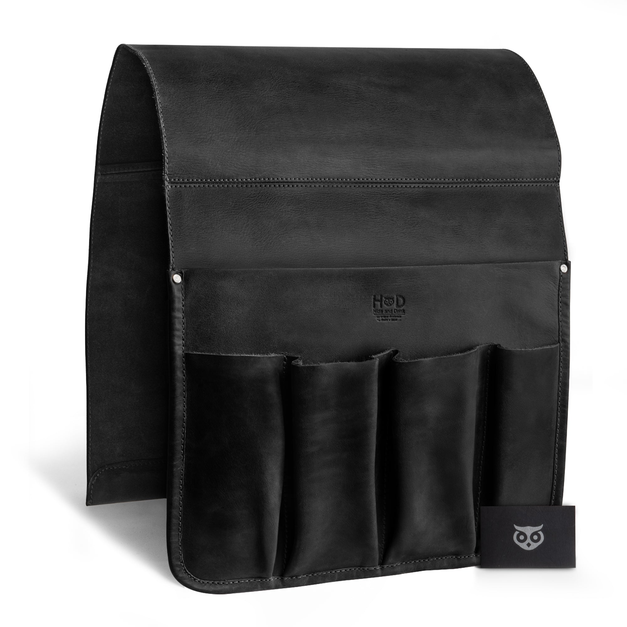 Hide & Drink Remote Control Holder showcasing its rich, dark leather and stylish pockets for remotes and magazines. This artistic piece exemplifies handmade craftsmanship from La Antigua Guatemala, emphasizing its role as a sophisticated sofa armrest organizer pouch.