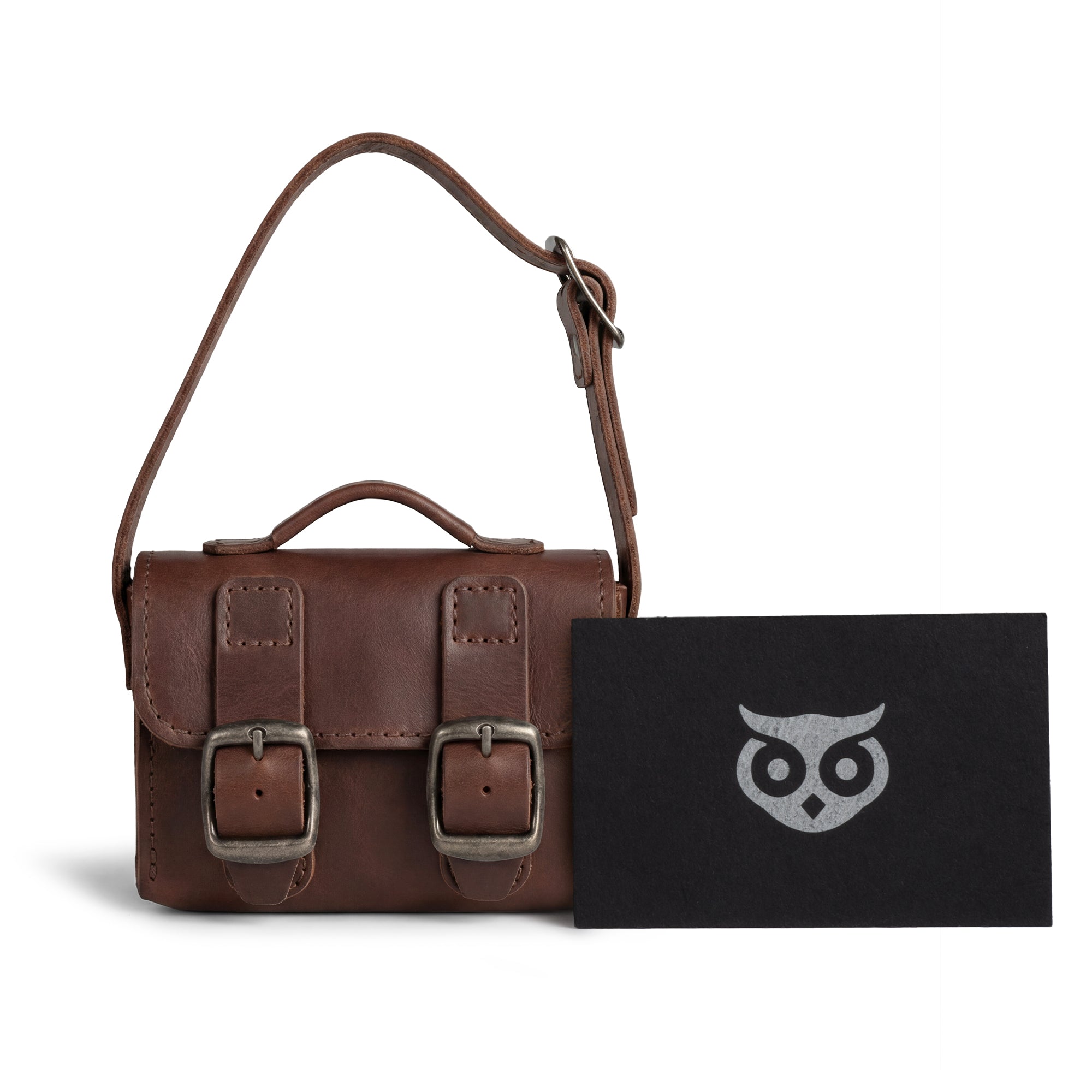 The Tiny Messenger Bag by Hide & Drink, displayed with additional tags. This Mini Messenger Bag Charm made from Full Grain Leather serves as a stylish keychain or handbag accessory. Artisan crafted in La Antigua Guatemala, showcasing small batch production and meticulous care.