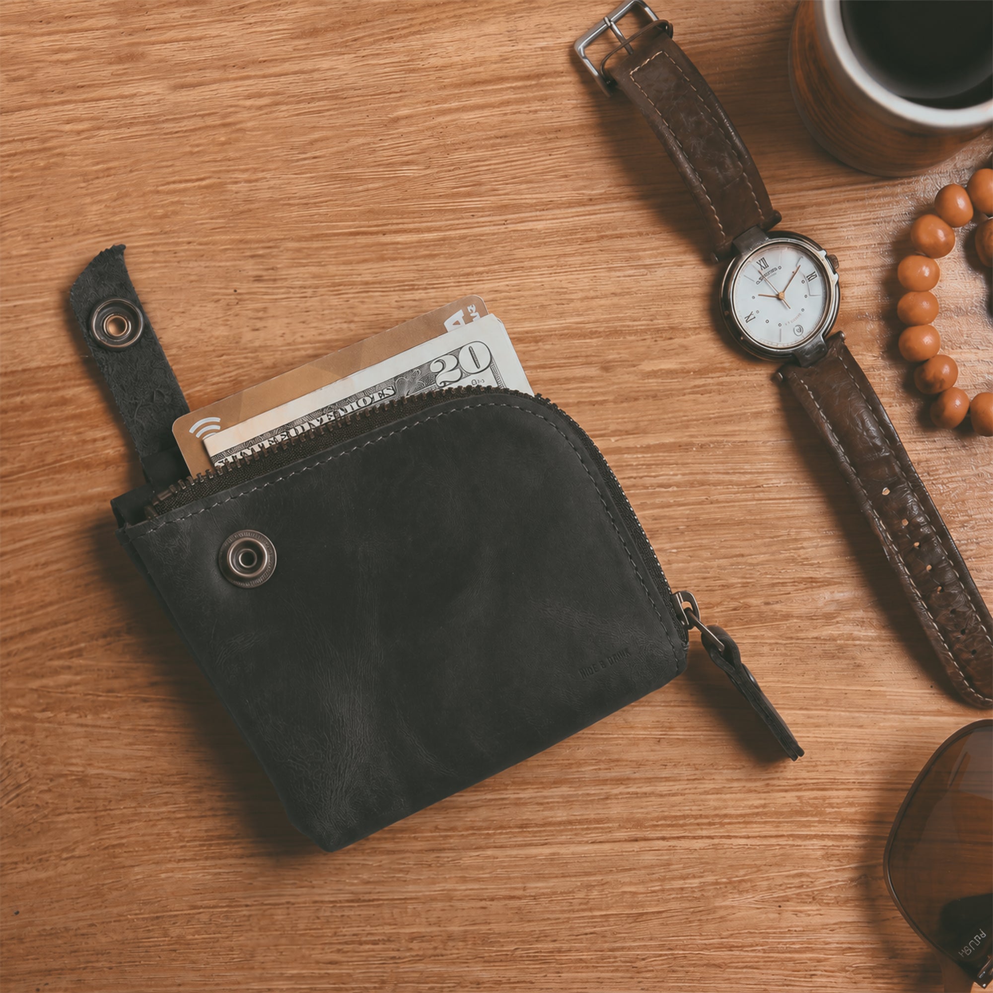Side view of the black Lion's Mane Zippered Wallet by Hide & Drink, showcasing its elegant finish and artisan craftsmanship. A great choice for anyone in need of a practical cash holder.