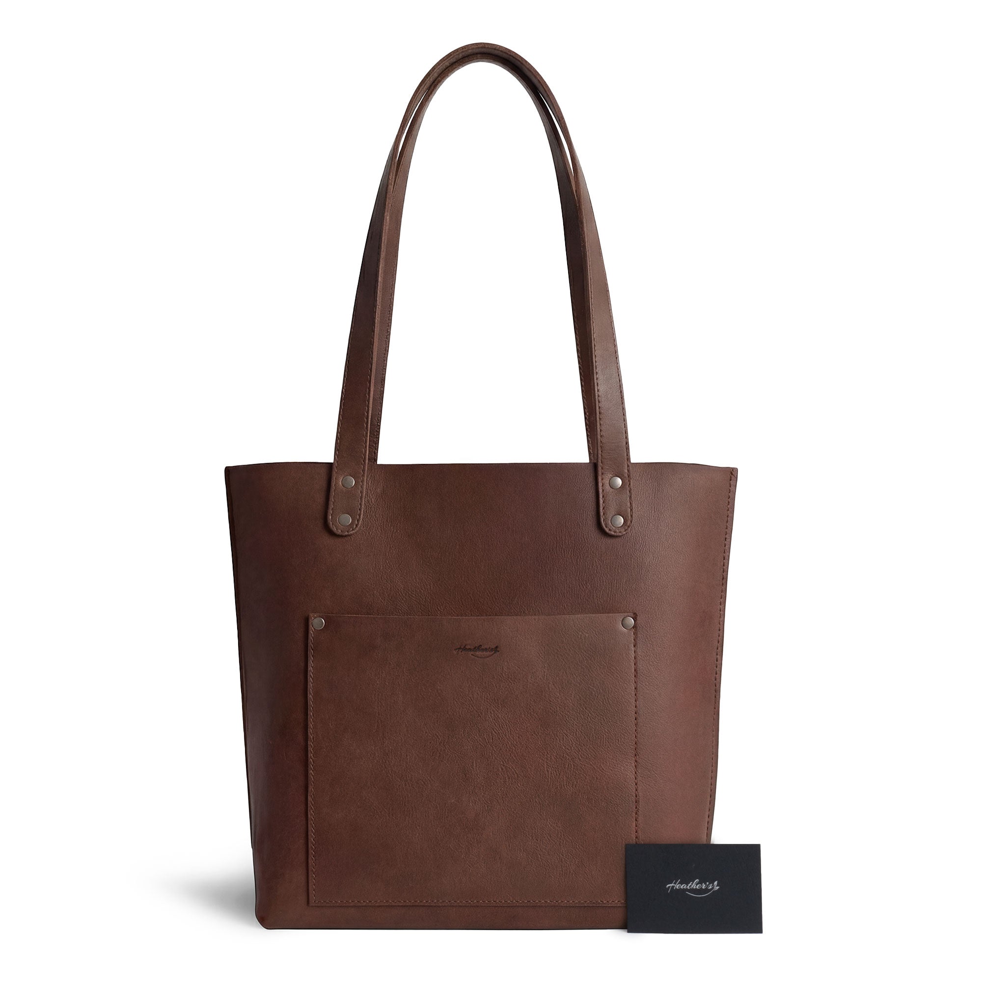 Heather's Minimalist Tote Bag With Pouch shown with a tag showcasing its artisan roots. This Classic Tote Bag Shoulder Bag for Women with Pouch is a symbol of small batch production made from full grain leather, hand cut and hand sewn just for you.