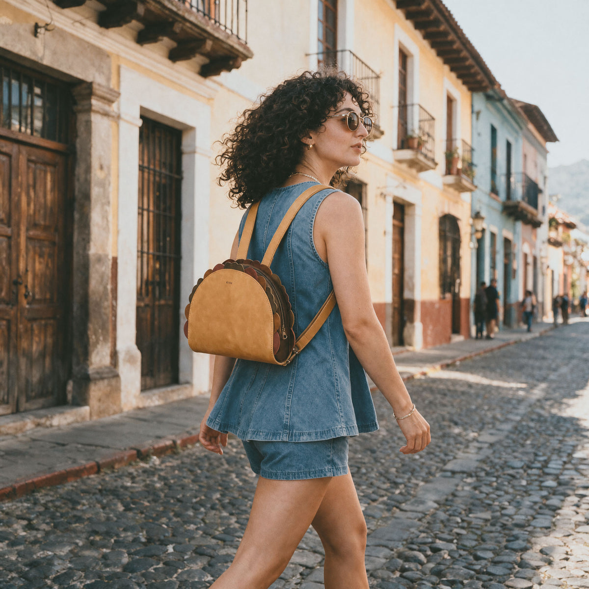 Woman wearing the Hide & Drink Taco Backpack while walking on a cobblestone street, a Taco Backpack and Fashion Zippered Bag with Carry Pack with Adjustable Shoulder Straps, Fun Carryalls style, Casual Daypack design, and Travel Accessory appeal; crafted from Full Grain Leather by StockyardX through Small Batch Production, Hand Cut and Hand Sewn with Fire Branded Artisan details, Handmade in La Antigua Guatemala & Oaxaca Mexico.