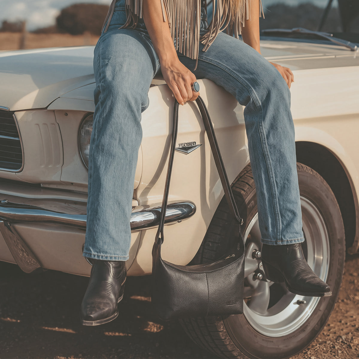 Model wearing the Austin Genuine The Mueller Hobo Shoulder Bag as a casual black shoulder bag, showcasing Full Grain Leather, StockyardX Artisan style, Small Batch Production, Hand Cut, Hand Sewn, Fire Branded craftsmanship, Handmade in La Antigua Guatemala & Oaxaca Mexico.