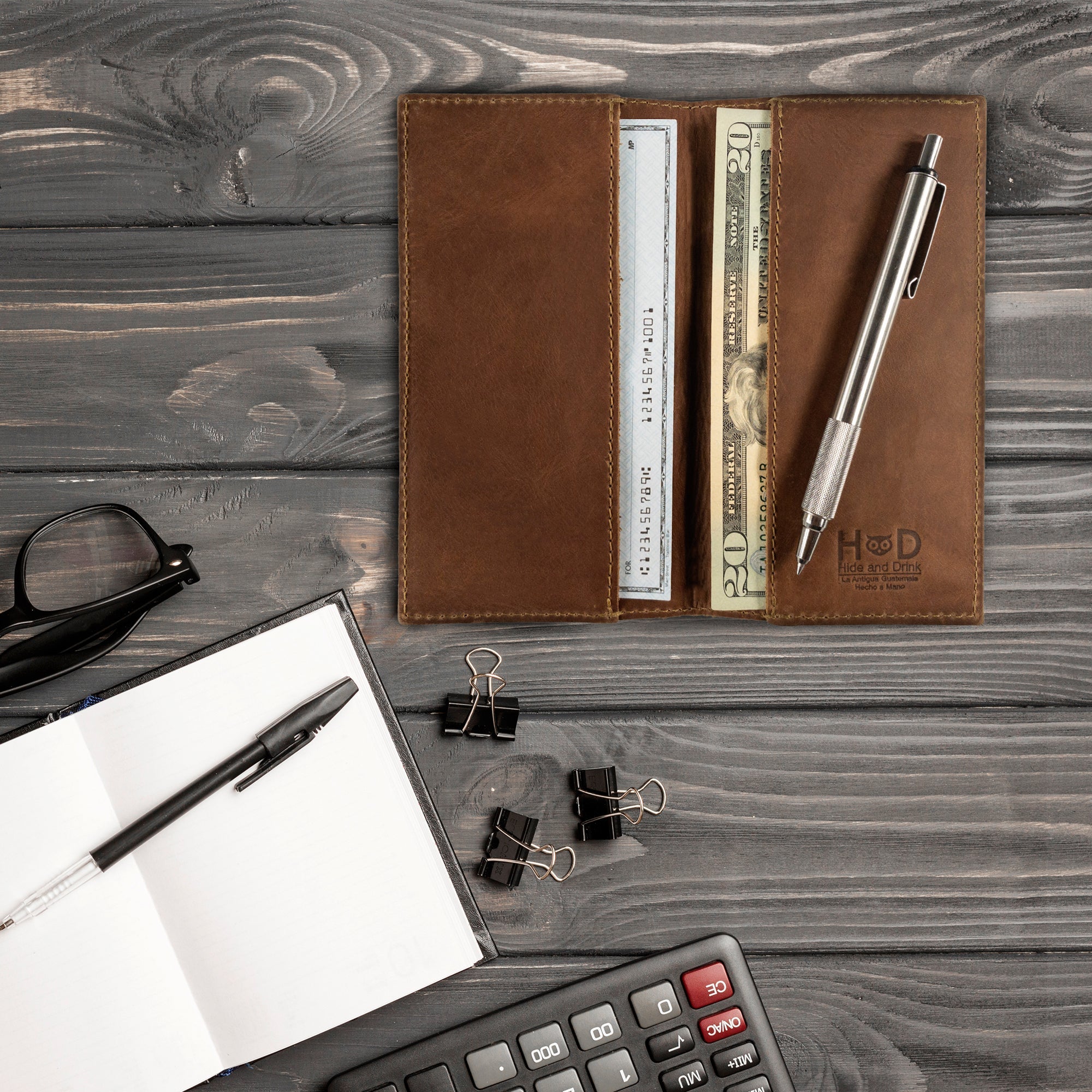 Close-up of the brown Checkbook Leather Cover by Hide & Drink, designed as a minimalist organizer for standard checkbooks. Crafted from full grain leather, this handmade piece reflects artisan craftsmanship from La Antigua Guatemala and Oaxaca Mexico, showcasing small batch production.