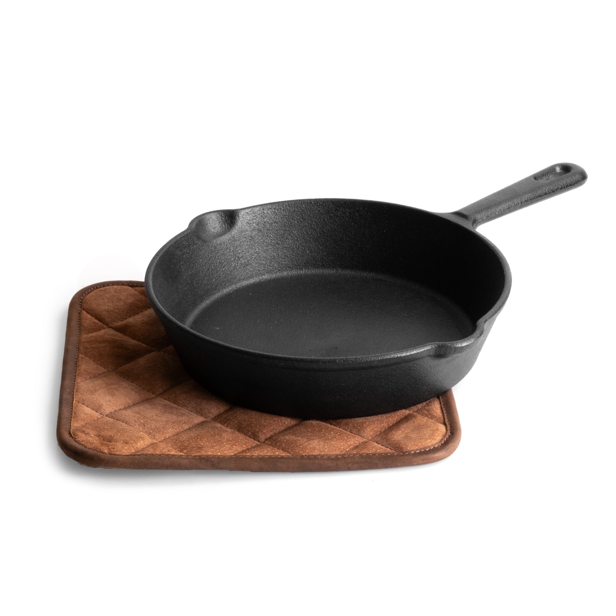 A cast iron skillet resting on the Cast Leather Co. Squared Hot Pot Pad, showcasing its heat-resistant features. The Squared Oven Mitt Heat Resistant, Hot Pot Pad (Potholder) is perfect for bakery supplies, made from full grain leather and sheepskin, highlighting stockyardX's commitment to small batch production. Handmade and artisan-crafted in La Antigua Guatemala & Oaxaca Mexico.