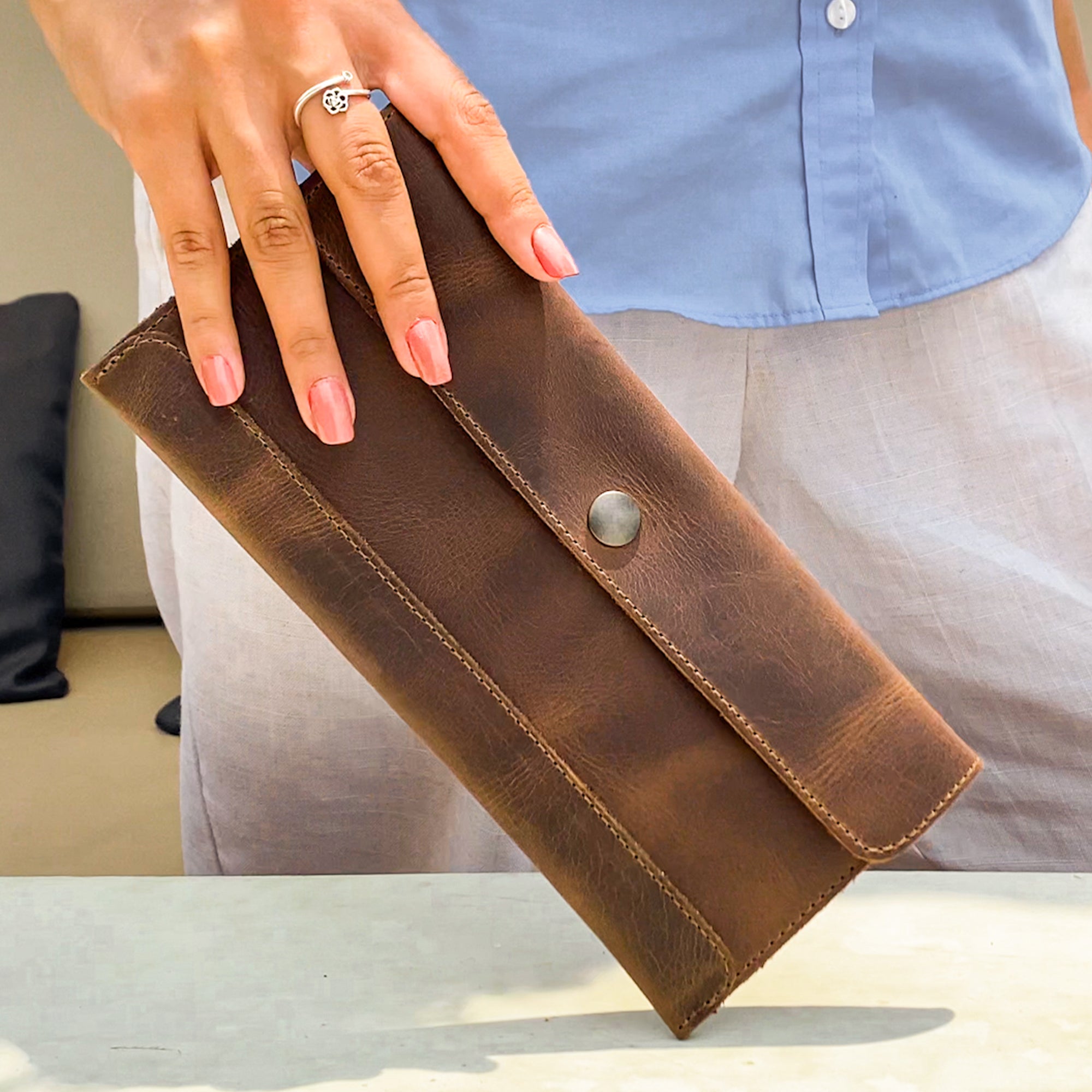 A hand model holds Hide & Drink's Travel Hand Wallet, demonstrating its sleek Full Grain Leather design. Ideal for travelers, this artisan Travel Wallet exemplifies Hand Sewn craftsmanship and is made with care in La Antigua Guatemala & Oaxaca Mexico.