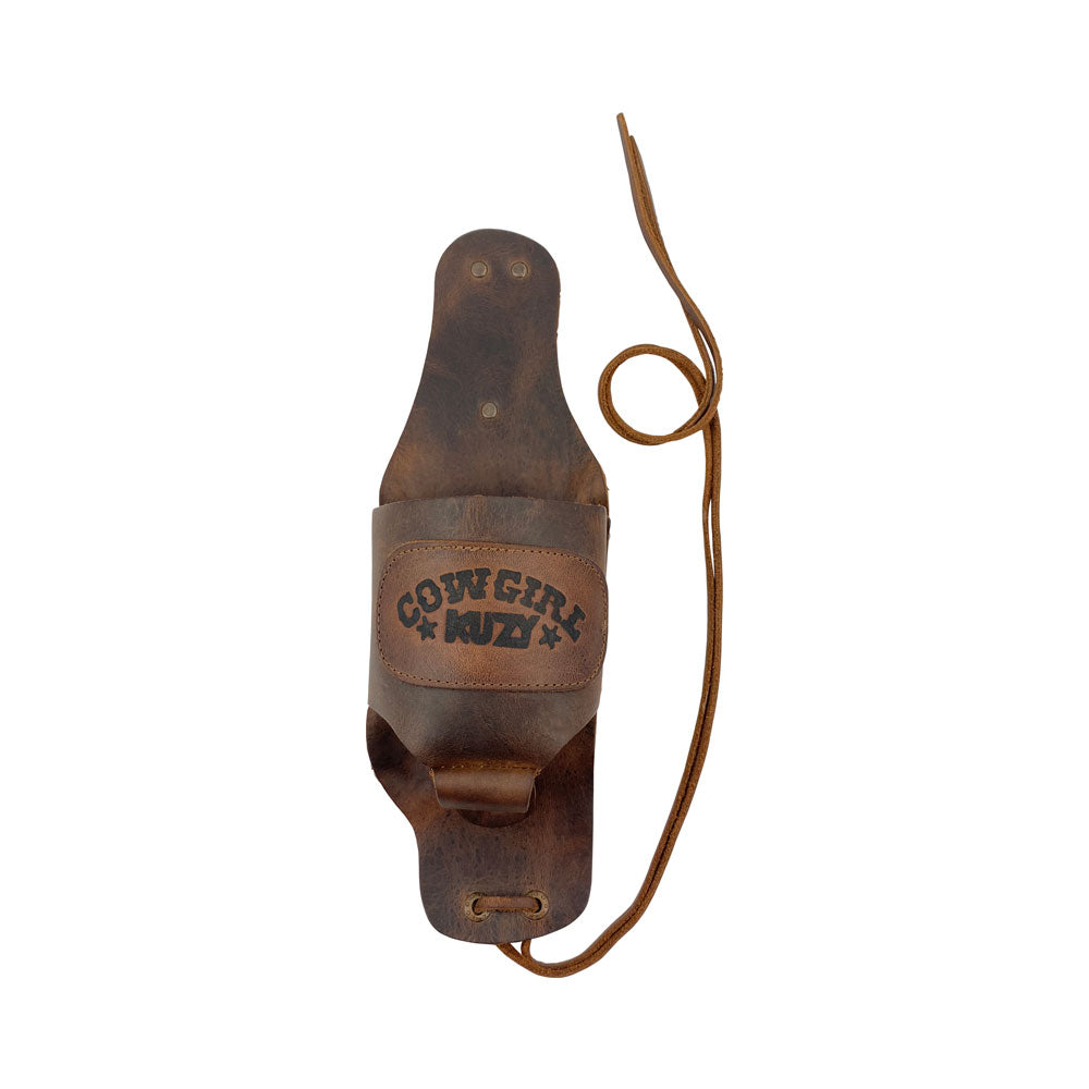 The Cowgirl Buzy Beer Holster from Hide & Drink showcases a stylish design crafted from full grain leather, perfect as a handsfree beverage holder. This artisan creation reflects old school women's badass style, featuring a bottle leg grip and fire-branded mark, made in La Antigua Guatemala & Oaxaca Mexico.