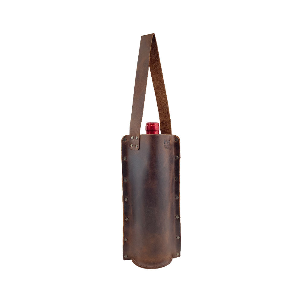 Rustic Wine Carrier For Standard 750ml Bordeaux Bottle by Hide & Drink, showcasing the Single Wine Carrier crafted from Full Grain Leather. This beautiful piece features small batch production techniques, hand cut and sewn details, and is fire branded by artisans, handmade in La Antigua Guatemala & Oaxaca Mexico.