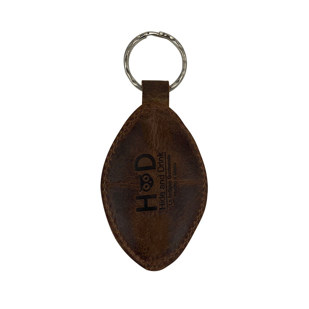 Back view of the Football Key Chain crafted from Full Grain Leather by Hide & Drink, highlighting the artisan craftsmanship. This fashionable accessory is a great gift for sports enthusiasts and includes tags Football Keychain, Small Batch Production, Hand Cut, Hand Sewn, Fire Branded, Artisan, Handmade in La Antigua Guatemala & Oaxaca Mexico.