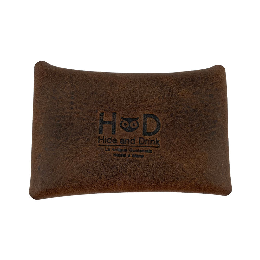 The Hide & Drink Envelope Coin Case with a branded logo, embodies rustic leather design and a modern touch. This full grain leather piece is handcrafted in La Antigua Guatemala & Oaxaca Mexico, ensuring high-quality, artisan craftsmanship.