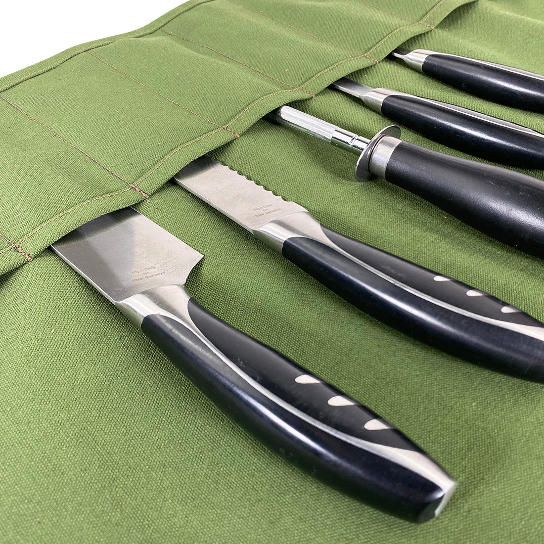 Detail of knives secured in the Cast Leather Co. Knife Roll Bag with durable water-resistant canvas. This portable knife roll bag, with 10 pockets, offers protection for sharp cooking items and features a detachable shoulder strap. Handmade in La Antigua Guatemala & Oaxaca Mexico.