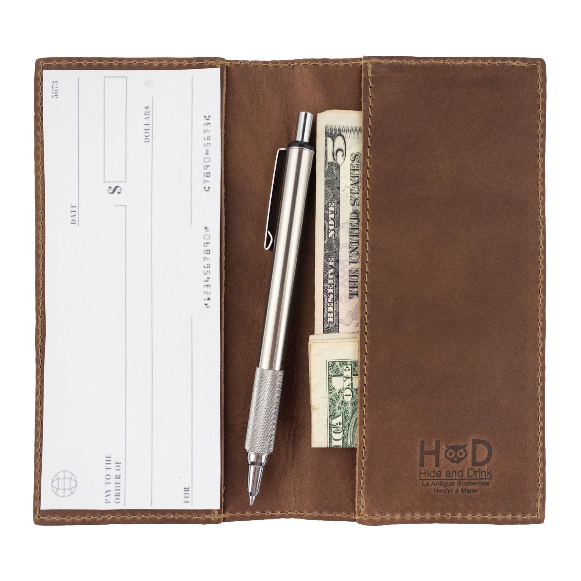 Checkbook Leather Cover by Hide & Drink, featuring a rustic brown design, serves as a minimalist organizer for standard checkbooks. This artisan product, crafted from full grain leather, is handmade in La Antigua Guatemala and Oaxaca Mexico, emphasizing the tradition of small batch production.