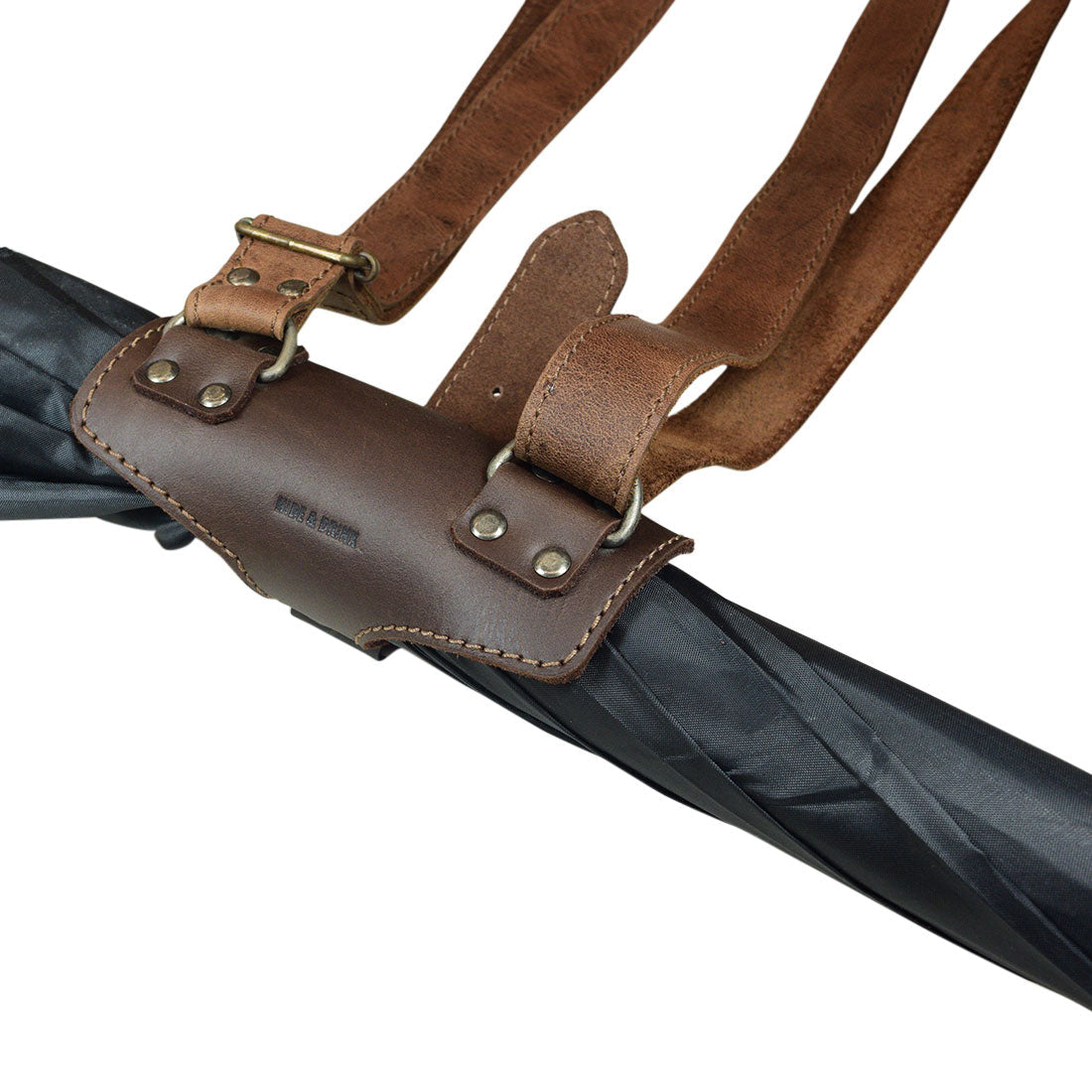 Hide & Drink Umbrella Strap Holder being used to hold an umbrella, showcasing its adjustable strap and premium full grain leather. This urban vintage accessory is crafted through small batch production with hand cut, hand sewn features, fire branded, and handmade in La Antigua Guatemala & Oaxaca Mexico.