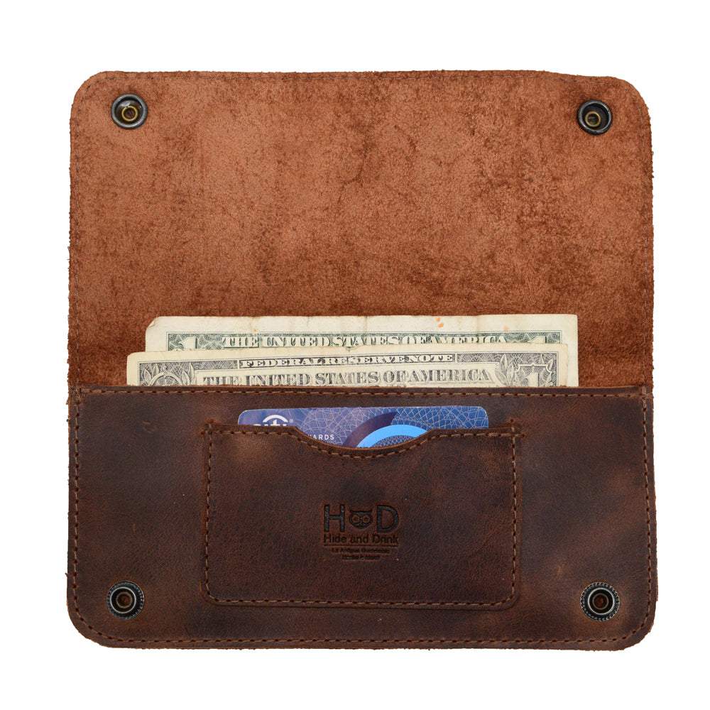 Inside view of the Brown Double Snap Folio Wallet by Hide & Drink, displaying cash and a card in its well-crafted full grain leather design. This rectangular flat bill holder with card slot functions beautifully as a night bag and travel accessory. Handmade in La Antigua Guatemala & Oaxaca Mexico, it reflects small batch production with fire branded quality.