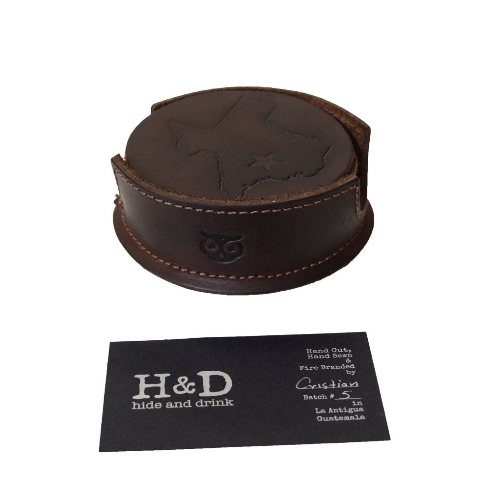 The Texas State Coasters (6-Pack) by Hide & Drink, featuring a close-up of the product with branding details. This image highlights the Durable Thick Leather quality and Fire Branded craftsmanship, emphasizing Small Batch Production and artisan skills from La Antigua Guatemala & Oaxaca Mexico.