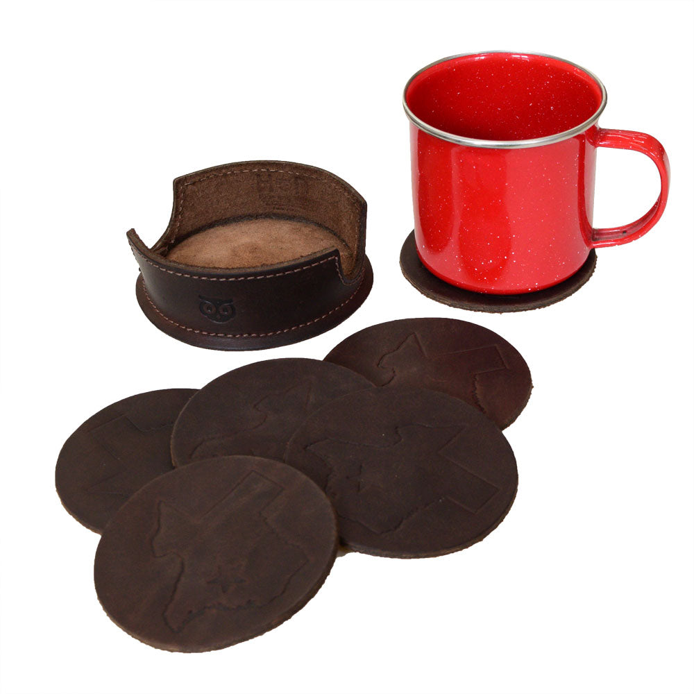 A cozy setting featuring the Texas State Coasters (6-Pack) by Hide & Drink alongside a vintage red cup, showcasing the Durable Thick Leather and Full Grain Leather craftsmanship. This set represents a commitment to Small Batch Production and artisan quality, handmade in La Antigua Guatemala & Oaxaca Mexico.