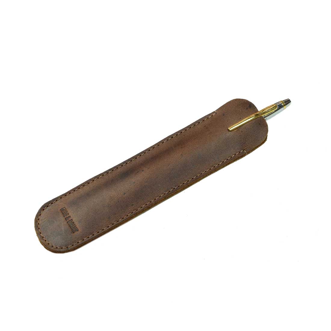 The Vintage Pen Sleeve by Hide & Drink is elegantly displayed with a pen, demonstrating its rustic charm made from durable Full Grain Leather. An ideal accessory for bookworms, showcasing the beauty of small batch production and artisan workmanship.