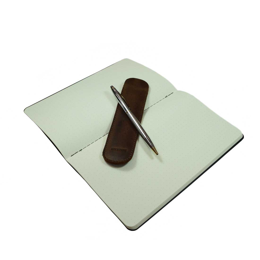 Open notebook featuring the Vintage Pen Sleeve with a pen, highlighting its practicality as a must-have office essential. This Hide & Drink item is crafted from Full Grain Leather, showcasing artisanal skills with its handmade construction in La Antigua Guatemala & Oaxaca Mexico.