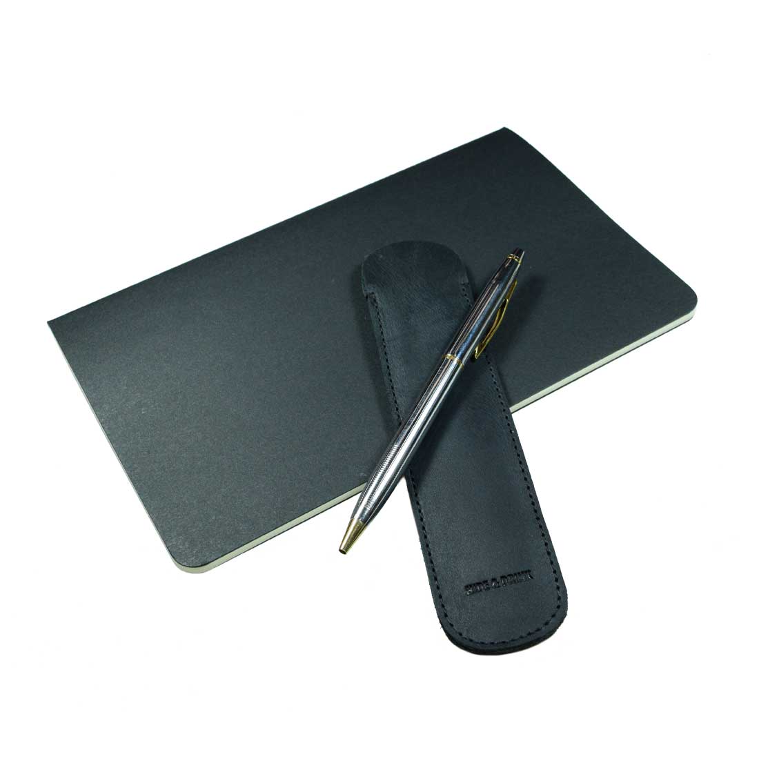 The Vintage Pen Sleeve by Hide & Drink is paired with a notebook, showcasing its durability and style as a must-have accessory for anyone who loves writing. This artisan-crafted product embodies quality and craftsmanship.