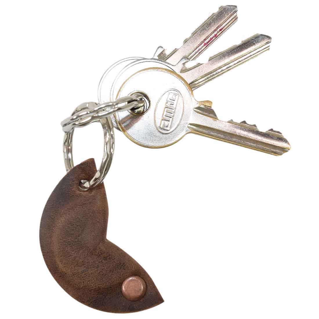A Fidget Cashew Keychain by Hide & Drink hangs from keys, showcasing its cute design and durable Full Grain Leather. This key holder acts as a Good Luck Charm, perfect for anyone who appreciates artisan craftsmanship. StockyardX's small batch production ensures quality, with each piece hand cut, hand sewn, and fire branded, reflecting the handcrafted nature of products made in La Antigua Guatemala and Oaxaca Mexico.
