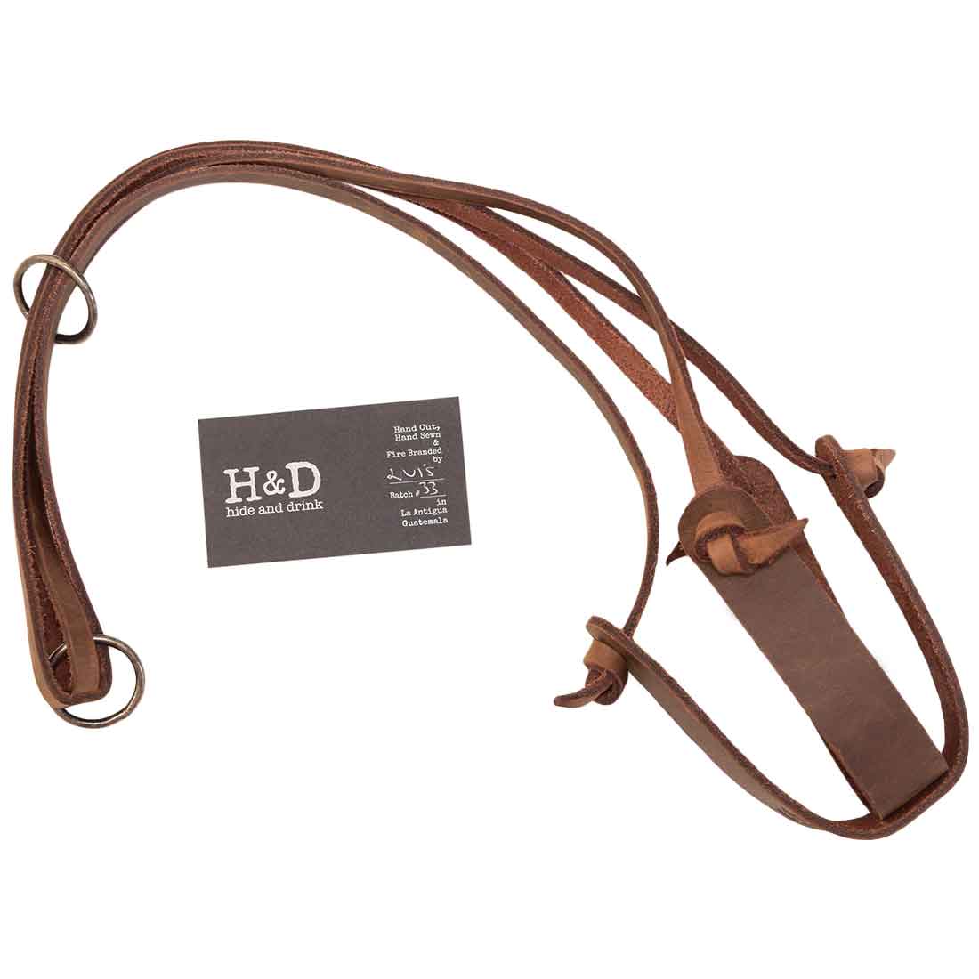 The Hanging Plant Holder from Hide & Drink displayed with its branding card, emphasizing the authentic craftsmanship behind the product. Crafted from Fine Full Grain Leather, this Plant Holder is a perfect Plant Hanger for enhancing indoor decoration. Enjoy the unique style derived from small batch production, with features that are hand cut, hand sewn, and fire branded by artisans in La Antigua Guatemala & Oaxaca Mexico.