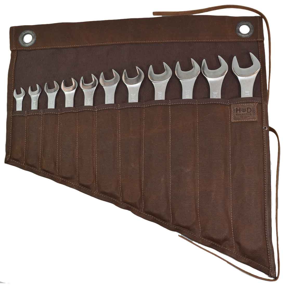 Hide & Drink's Wrench Roll (11 Pockets) showcasing a rustic design with 11 pockets to store wrenches. This Wrench Tool Roll features hanging storage for craftsmen, offering durable tool storage made from waterproof waxed canvas. Perfect as a rustic organizer, this artisan product showcases small batch production, hand cut and hand sewn craftsmanship, and is fire branded, handmade in La Antigua Guatemala & Oaxaca Mexico.